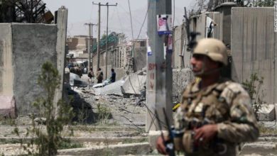 An Afghan security personnel stands guard at the site where a Taliban car bomb detonated at the entrance of a police station in Kabul, August 2019.
