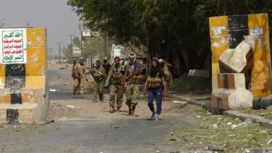 Armed Yemeni soldiers walk on.