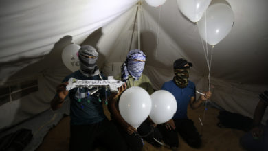 asked Palestinians calling themselves the "night confusion units" hold incendiary devices attached to balloons to be flown into Israel, near the Gaza-Israel border east of Rafah, September 2018.