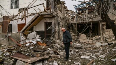 An elderly man stands in front of a destroyed house after shelling in the occupied Nagorno-Karabakh region's main city of Stepanakert.