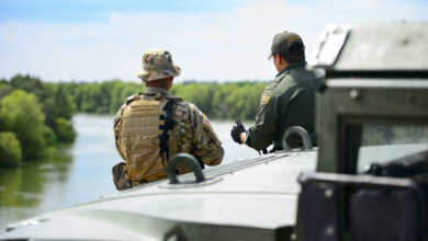 A Texas Guardsmen and a Customs and Border Patrol agent discuss the lay of the land on the shores of the Rio Grande River in Starr County, Texas.