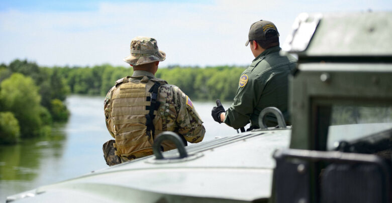 A Texas Guardsmen and a Customs and Border Patrol agent discuss the lay of the land on the shores of the Rio Grande River in Starr County, Texas.