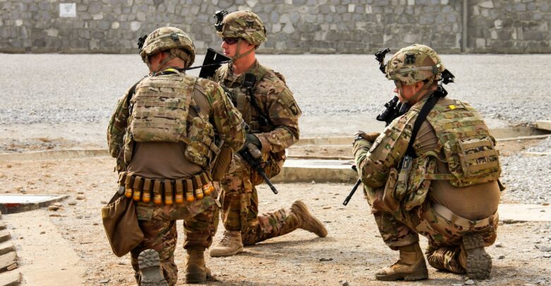 Three soldiers from the 3rd Brigade Combat Team, 101st Airborne Division (Air Assault), assigned to the Train, Advise, Assist Command - East security force, hold their positions and prepare for the landing of a UH-60 Black Hawk helicopter