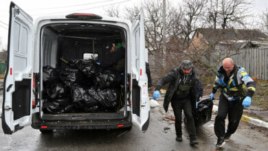Communal workers carry a body of a civilian man in town of Bucha