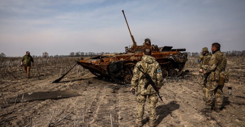 Ukrainian soldiers stand by a burnt Russian tank on the outskirts of Kyiv, on 31 March, 2022