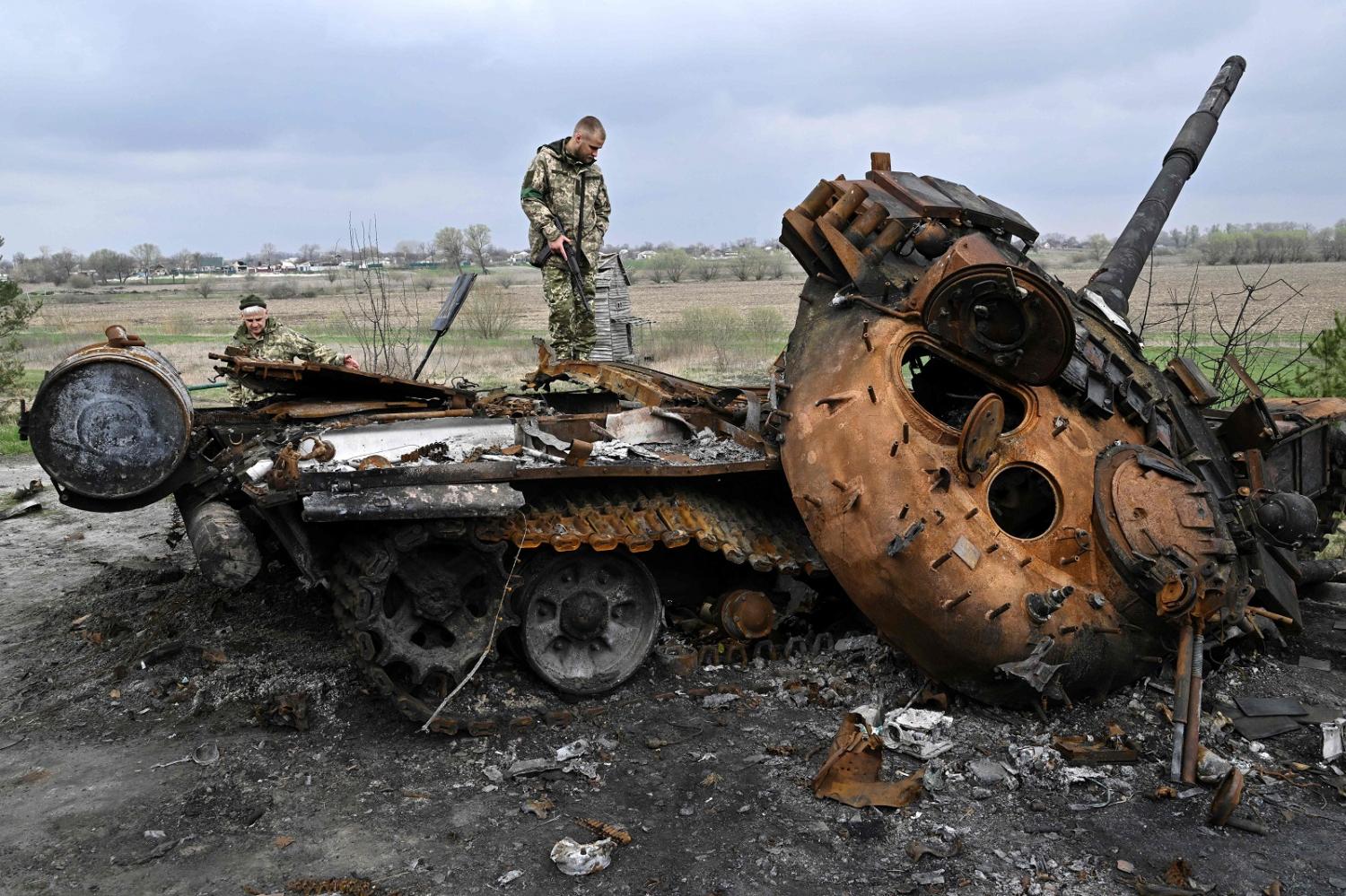 Ukrainian servicemen on a destroyed Russian tank