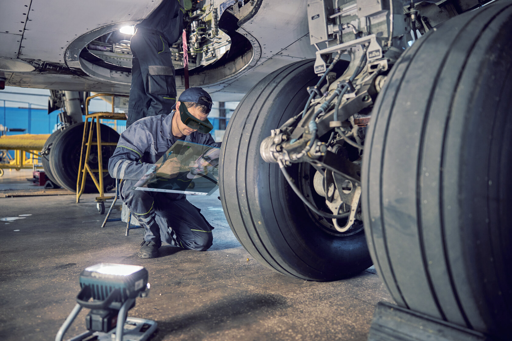 Personnel conducting aircraft maintenance using augmented reality goggles.