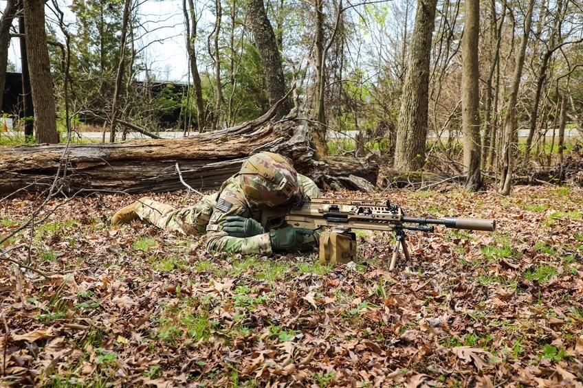 US soldier looks down sights of the new XM250 light machine gun