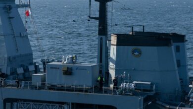 Part of the upper deck of Germany's Sachsen F-124 ship is seen on the photo. the laser weapon demonstrator, which looks like a giant rectangular box, is seen on the center left. The initials "MBDA" is written on its left side, and the name "Rheinmetall" is on the right. The sea, stretching over the horizon, serves as the background of the picture.