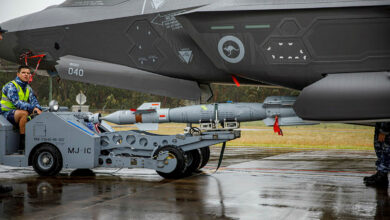 A technician (middle left) loads a BLU-111 (AUS) aerial bomb onto an F-35A Lightning II aircraft.