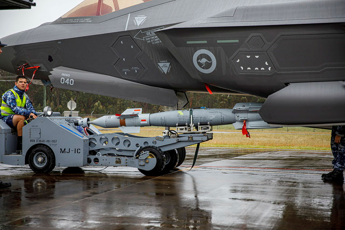 A technician (middle left) loads a BLU-111 (AUS) aerial bomb onto an F-35A Lightning II aircraft.
