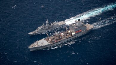 HMAS Anzac III sails alongside USNS Rappahannock. The photo is taken at a bird's eyeview. The sea is a deep blue.