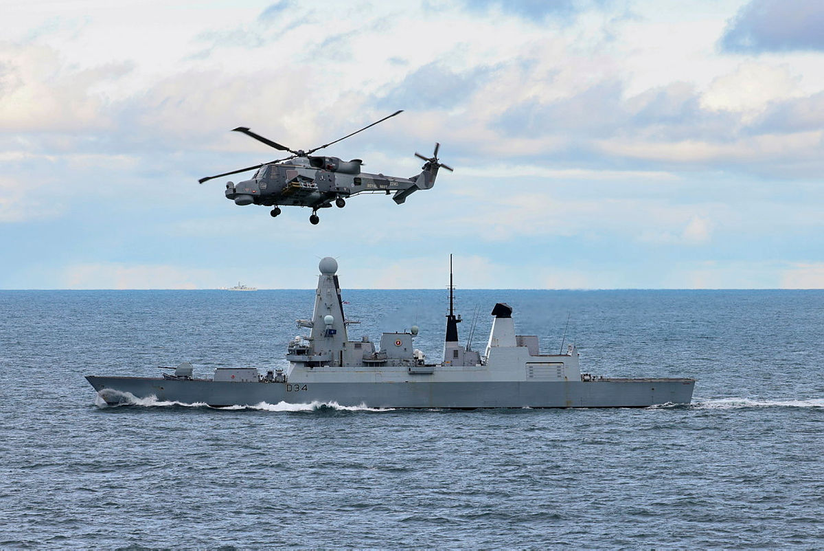 815 Wildcat fitted with Martlet missile flies above HMS Diamond.
