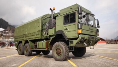 A Rheinmetall military truck is seen in parked in a lot. The truck is painted camouflage green.
