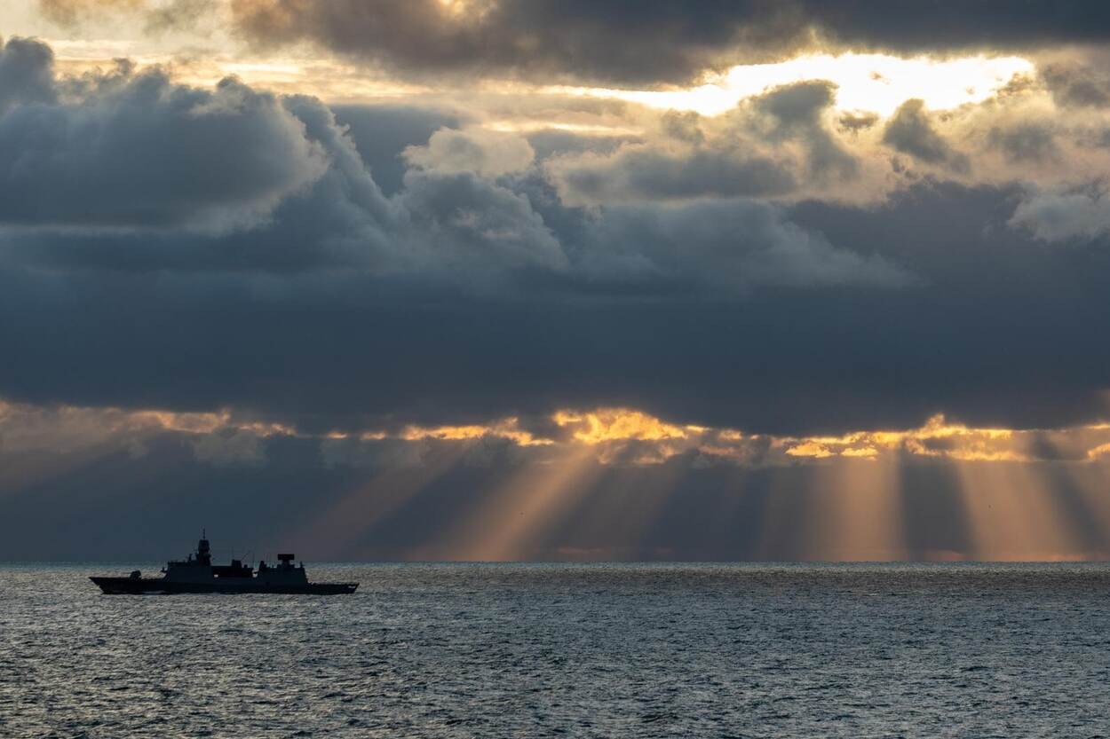 The Indian Air Force (IAF)'s newest air defense missile system has passed a series of test fires at Air Force Station Suryalanka. The locally-developed Surface-to-Air Missile for Assured Retaliation (SAMAR) An outline of a ship can be seen on the horizon sailing in calm waters as the sun begins to set. The sky is covered in dark blue clouds, and small pockets of light make the sun's golden rays shine down in the background. The water is dark blue.