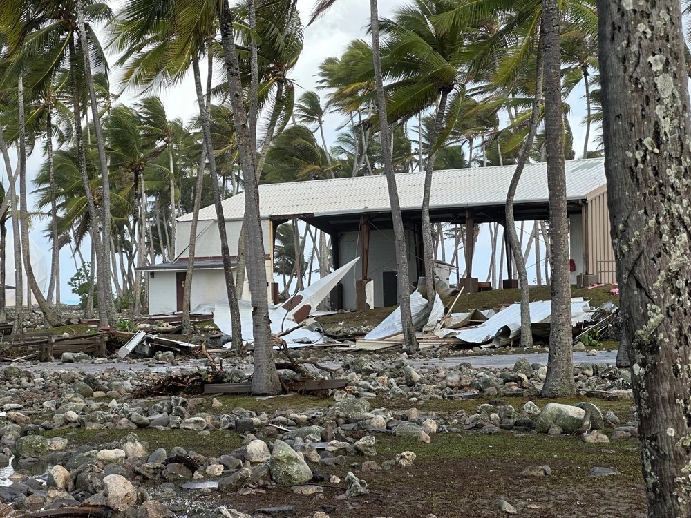 The Roi-Namur church steeple rests on the coral-strewn grounds on the opposite side of the Tradewinds Theater, background, from where it once stood