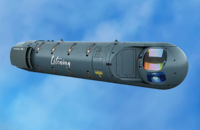 A LITENING 5 Target Pod. The capsule-shaped targetting system is painted gray-green and has "Litening" painted in white in the middle of it.