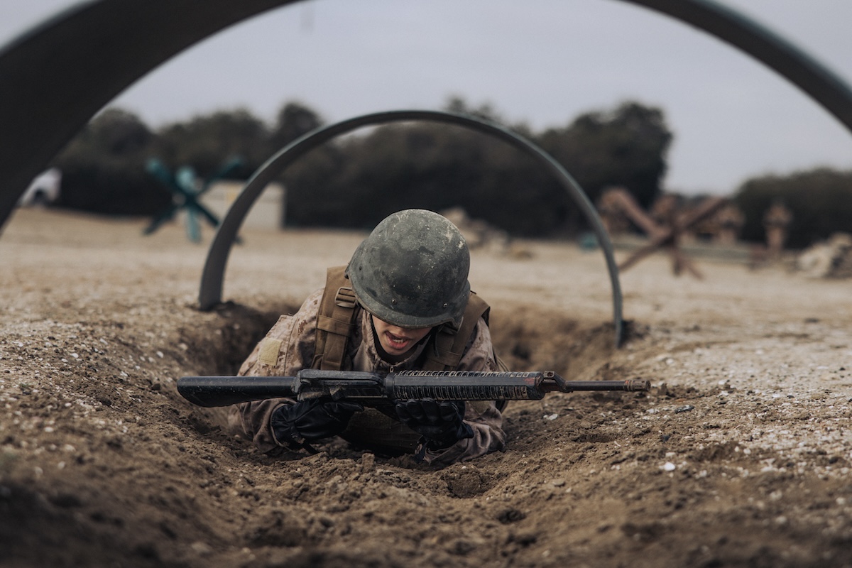 A US Marine Corps recruit crawls under an obstacle on the bayonet assault course at Marine Corps Recruit Depot San Diego, California