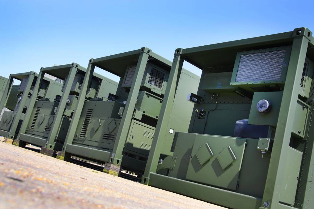 Marshall's Deployable Operations and Maintenance System (DOMS) are seen lined up on a flat surface area. The DOMS appear to be box-shaped containers painted in green.