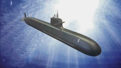 A computer-generated image of an S80 Plus-class submarine moving underwater. The submarine is painted black. The background is the blue water illuminated by white light from the surface.