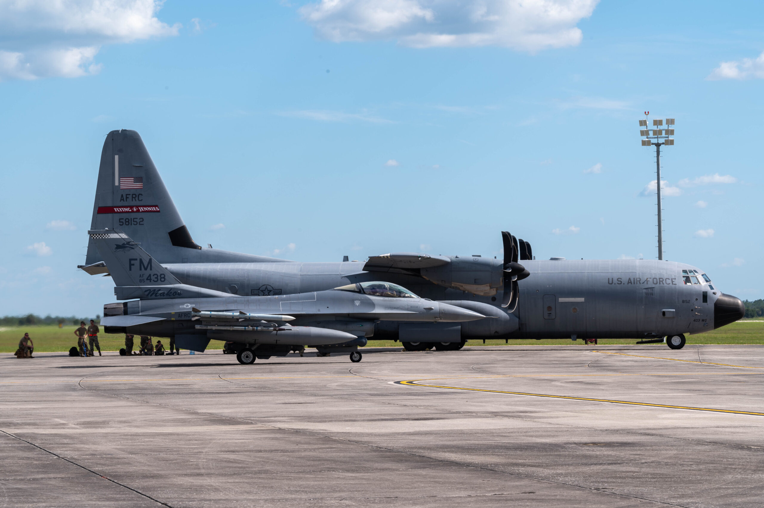 Airmen take a break in the shade after landing a C-130 cargo aircraft and refueling an F-16 fighter jet at Avon Park, Florida, June 6, 2022. Airmen nationwide participated in a week-long exercise in Jacksonville, Fla. called "Rally in the Swamp" coordinated by the 22nd Air Force. (U.S. Air Force photo by Staff Sgt. Timothy Leddick) (This photo has been edited to enhance the subjects)