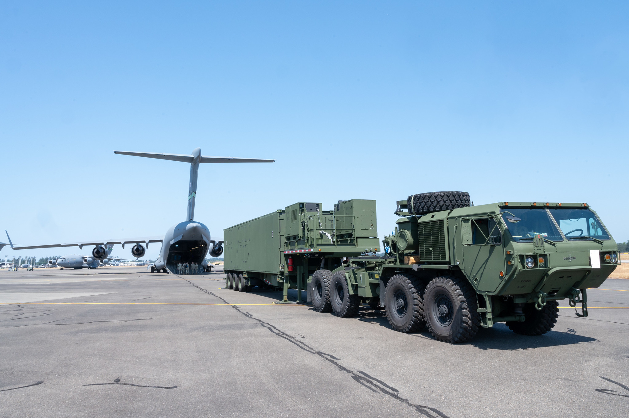 A green launcher of the Typhon missile parked behind a plane