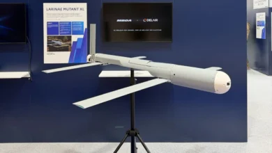 Mutant XL loitering munition displayed on a stand at an exhibition, showing its long airframe, extended folding wings, and streamlined nose against a blue MBDA–Delair booth backdrop