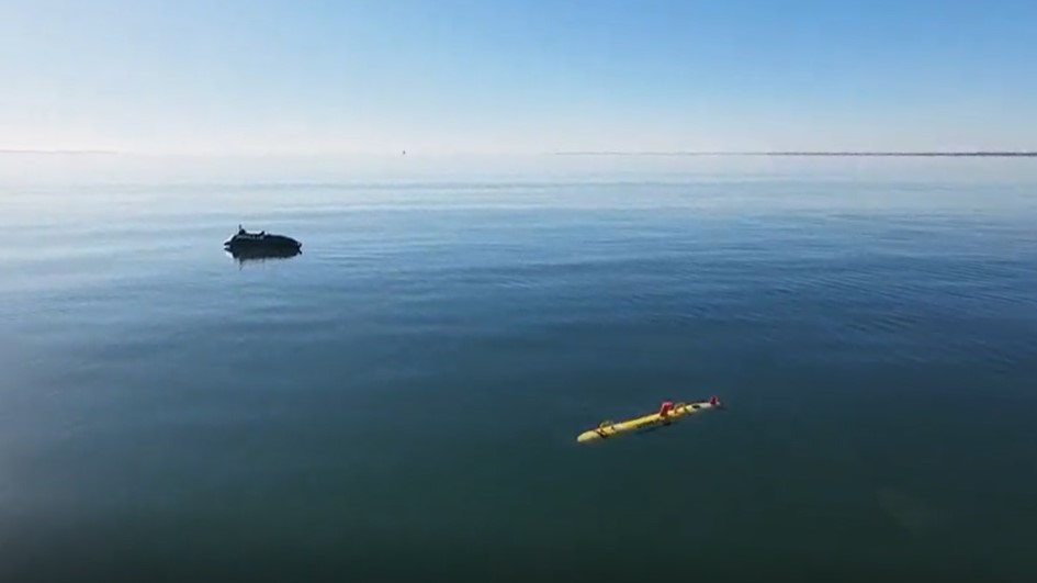 A ROMULUS 7 USV transiting the swells alongside a REMUS UUV during coordinated maritime autonomy trials. 