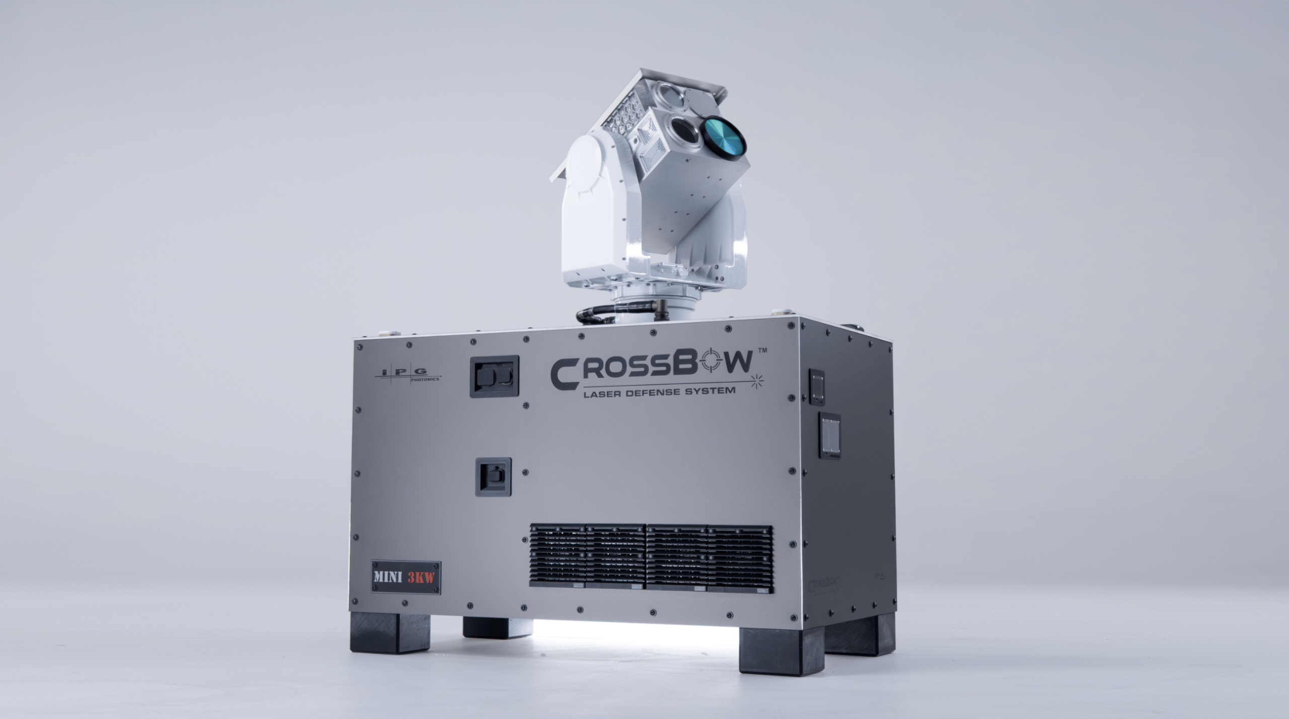 A compact laser defense system with a turret-mounted laser head, labeled "CROSSBOW," sitting on a metallic base.