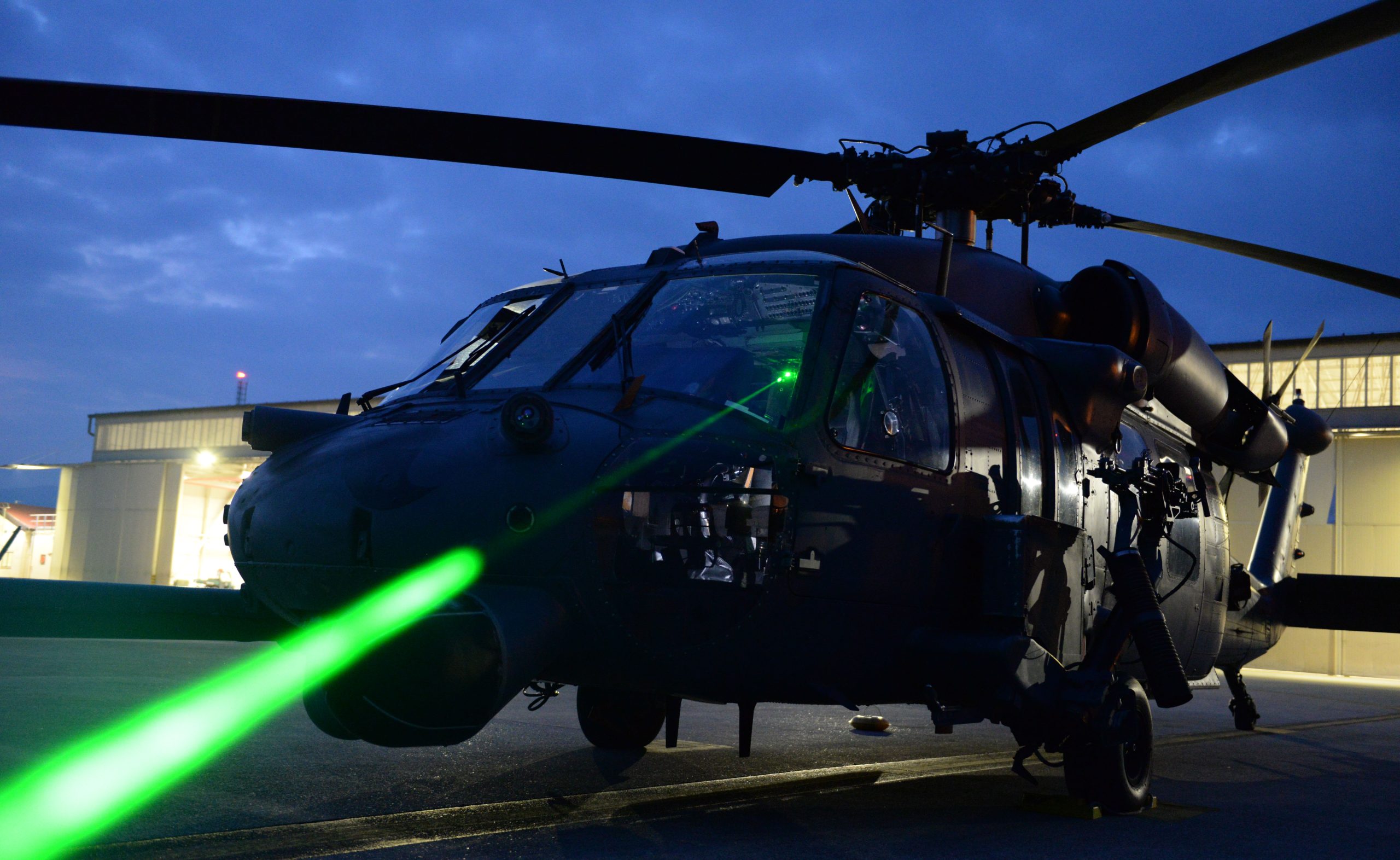 U.S. Air Force Master Sgt. Miguel Gibson, 31st Fighter Wing flight safety manager, demonstrates how pointing a laser at an HH-60 Pave Hawk can illuminate the cockpit at Aviano Air Base, Italy, October 12, 2023. Laser strikes on aircraft, often referred to as "lasing," have become a growing concern for aviation safety in recent years, as it can cause blindness, distraction and potential long-term eye damage to pilots and crew members. (U.S. Air Force photo by Airman 1st Class Hannah Stubblefield)